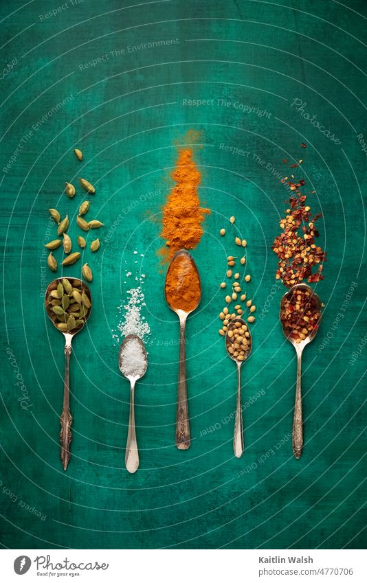 Spices and seasonings for cooking on vintage spoons and jade green background Food spices cardamom salt turmeric coriander red pepper cuisine Herbs and spices