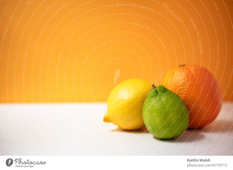 Fresh citrus fruit: lemon, lime, and orange with bold orange background healthy vitamin food nutrition yellow green fresh clean colorful plant vivid produce