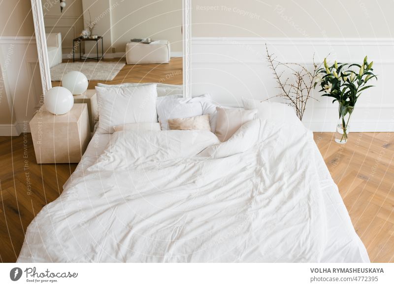 A double bed with white linens and beige pillows in a bright Scandinavian bedroom, a bed on the floor and flowers in a vase furniture modern house apartment