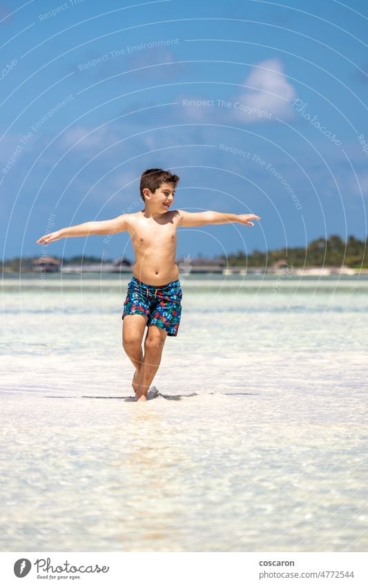 Funny kid running throw the water of a beach with open arms asia baby blue boy child childhood coast copy space cute family fun funny happy holiday island joy