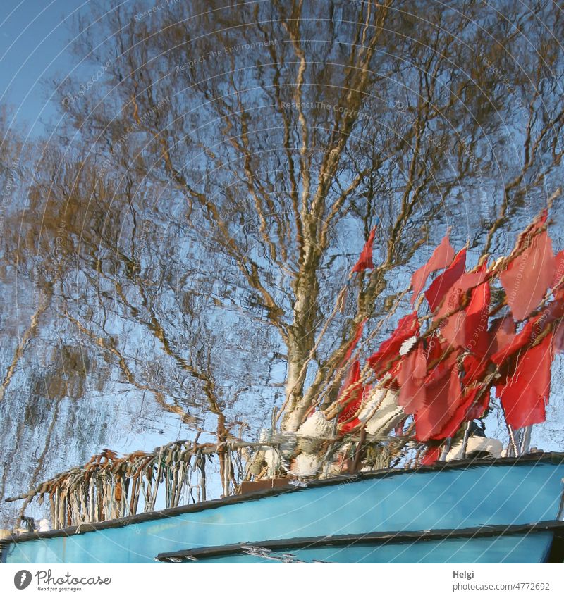 Reflection of fishing boat with red flags and hooks, in the background a tree against blue sky Fishing boat Water reflection Red Checkmark Tree Sky Detail