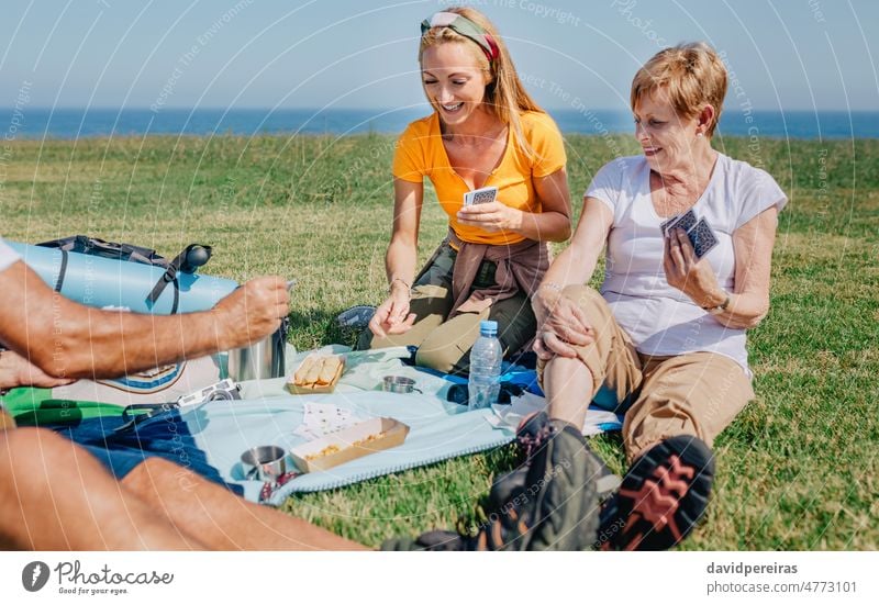 Young woman and senior woman playing cards in family during an excursion young women celebrating smiling poker happy fun outdoor generation adult together