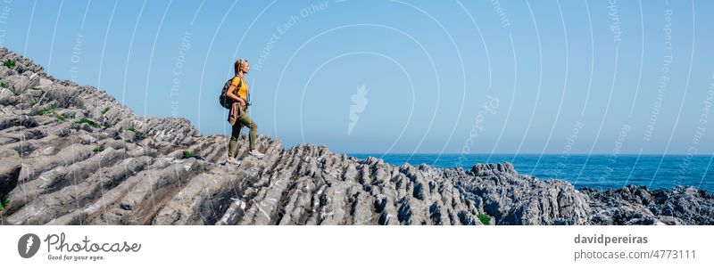 Woman with backpack walking through flysch rock landscape woman copy space young adult trekking hiking banner panorama panoramic web header seascape background