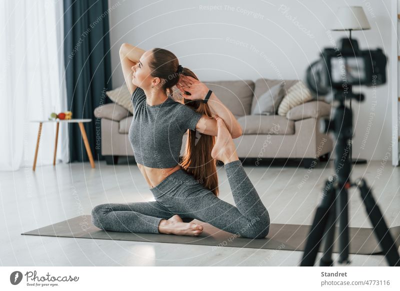 Doing lessons on camera. Young woman with slim body type and in yoga clothes is at home fitness healthy lifestyle photographic equipment blogger tripod sport