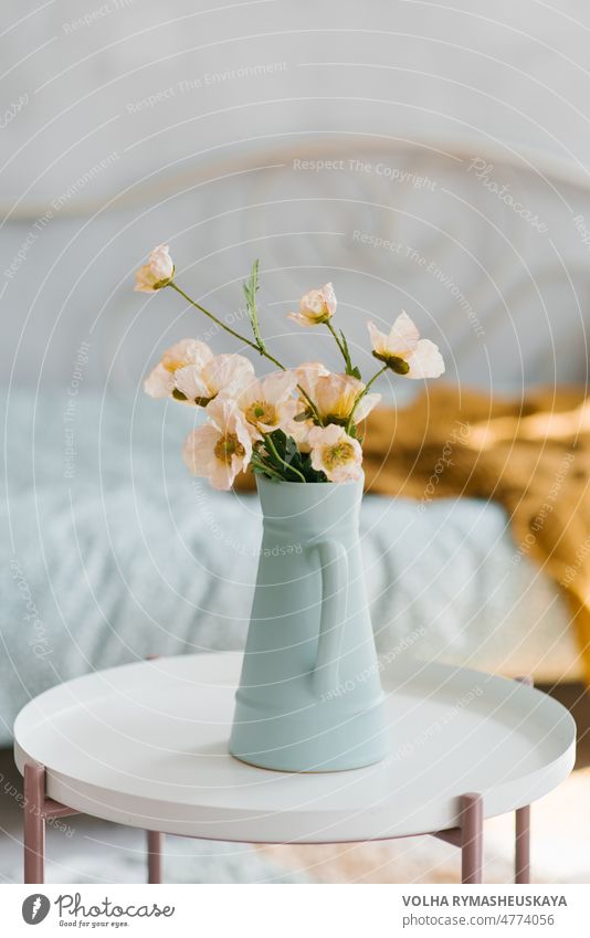 Artificial poppy flowers in a blue vase in the form of a jug on the coffee table in the interior of the room vintage floral nature background white plant summer