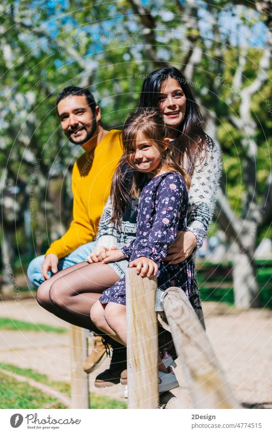 Happy family standing in green park while little girl looking at camera affection carrying children father shoulder together togetherness daughter free