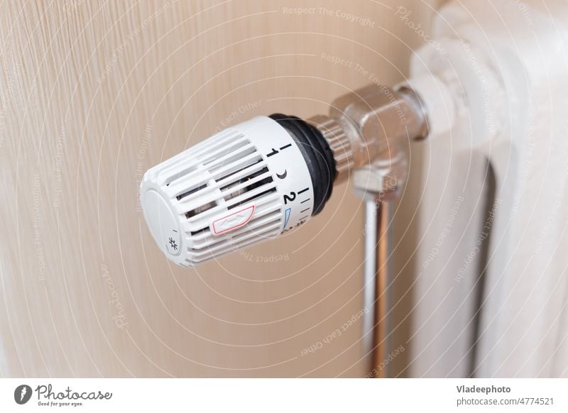 thermostatic valve on radiator close up temperature heat energy regulator white home room consumption cost cold heater winter control knob closeup regulate