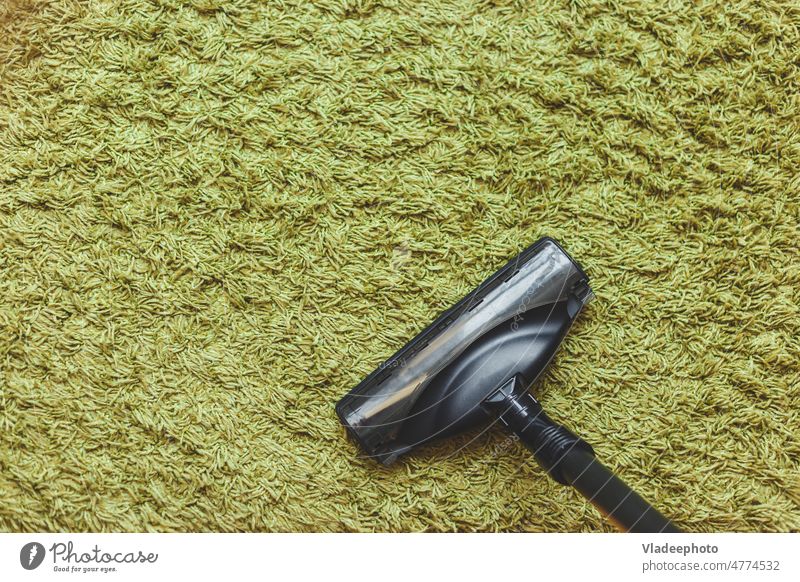 house cleaning concept with space for text. The head of a vacuum cleaner brush on the green carpet, the top view. room look vacuuming home interior appliances