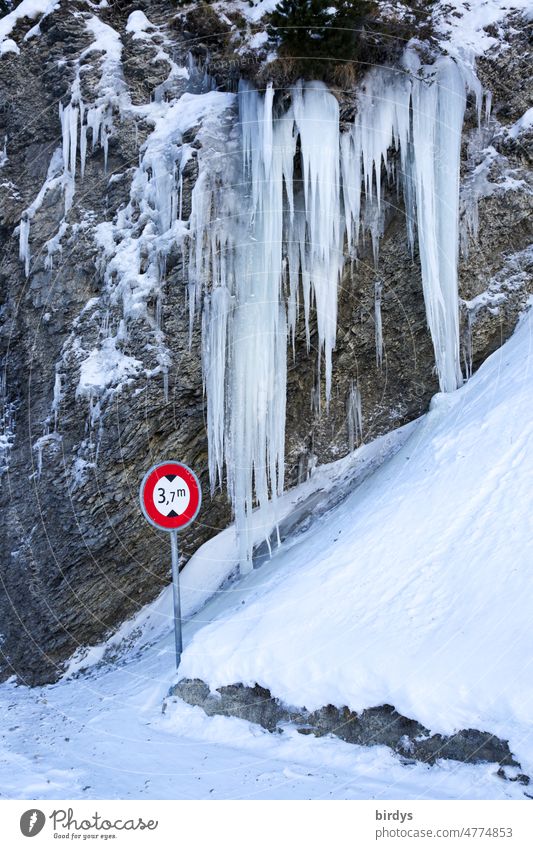 Record-breaking, gigantic icicles on a rock face, in front of it a traffic sign with height limit Icicle Gigantic Ice Frost Wall of rock Snow Road sign