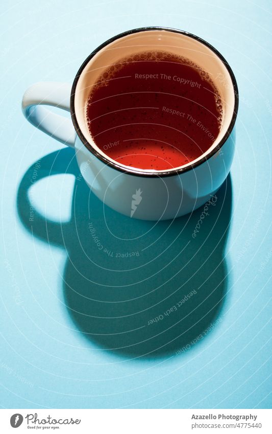 A cup of black tea on blue background under the bright sunlight. beverage breakfast brown caffeine ceylon china close up concept conceptual creative cup of tea