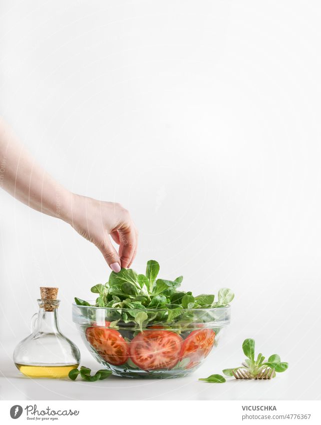 Woman hand preparing healthy food. Making healthy salad bowl woman making green lettuce leaves tomatoes oil glass white background front view fresh freshness