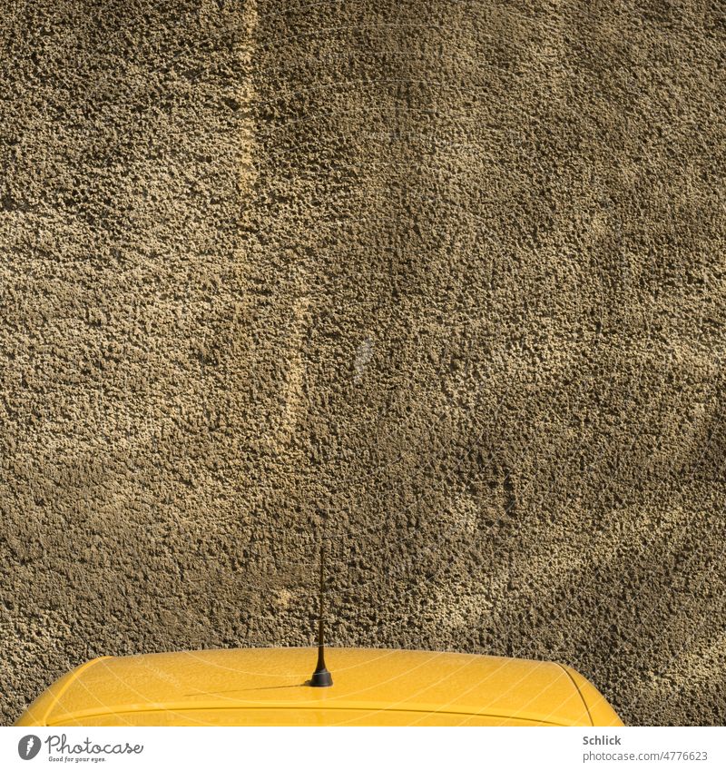 Yellow car roof with antenna in front of wall Car roof Wall (building) Antenna Aoto Parking Colour photo Exterior shot Deserted Wall (barrier) Parking lot