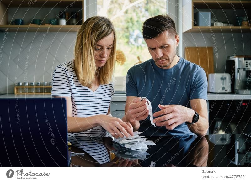 Man and woman looking at payment bills in the kitchen family budget calculate home finance planning worried tax table money loan bank debt people problem