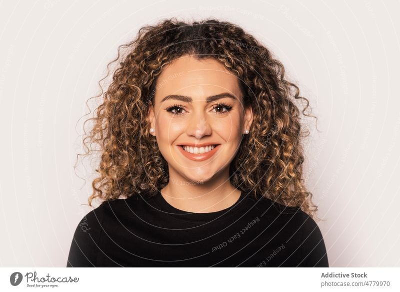 Smiling blonde woman with curly hair in studio smile cheerful happy positive optimist young appearance casual style glad bright joy portrait colorful