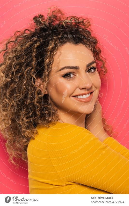 Smiling woman with curly hair in studio smile cheerful happy positive optimist young appearance casual style glad bright joy portrait colorful toothy smile