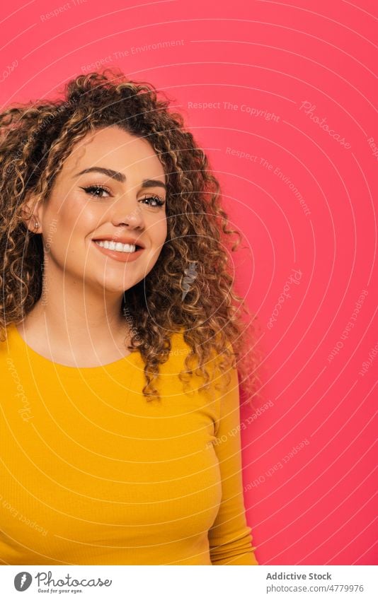 Smiling woman with curly hair in studio smile cheerful happy positive optimist young appearance casual style glad bright joy portrait colorful toothy smile