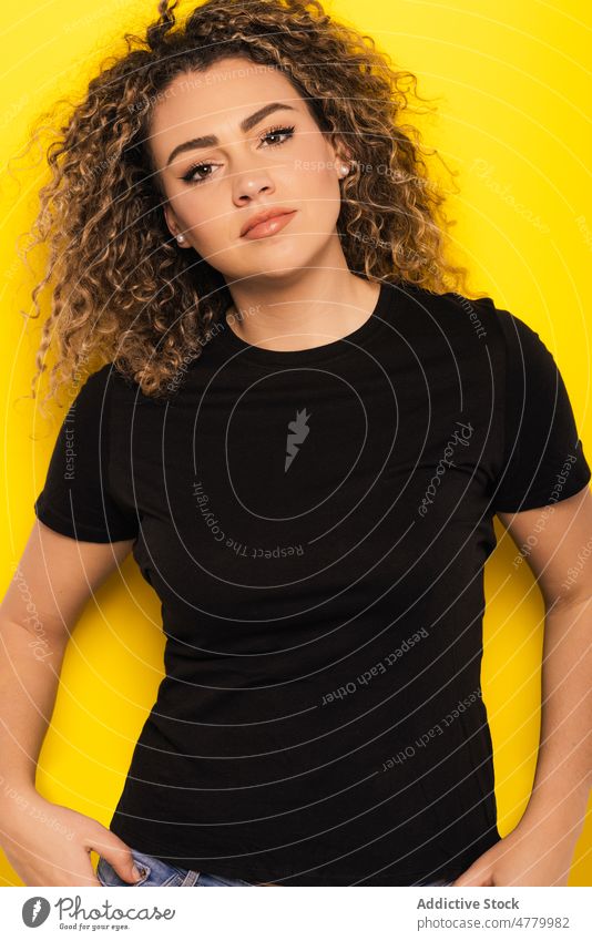 Serious blonde woman with curly hair in studio optimist young appearance casual style glad bright portrait colorful trendy model vivid outfit personality