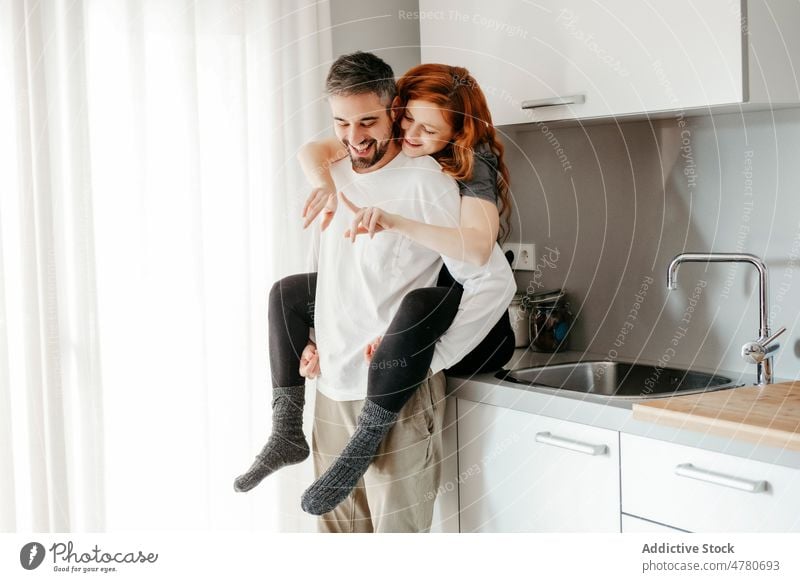 Loving couple hugging in kitchen relationship love bonding cuddle romantic affection redhead piggyback caress embrace fondness together home smile spend time