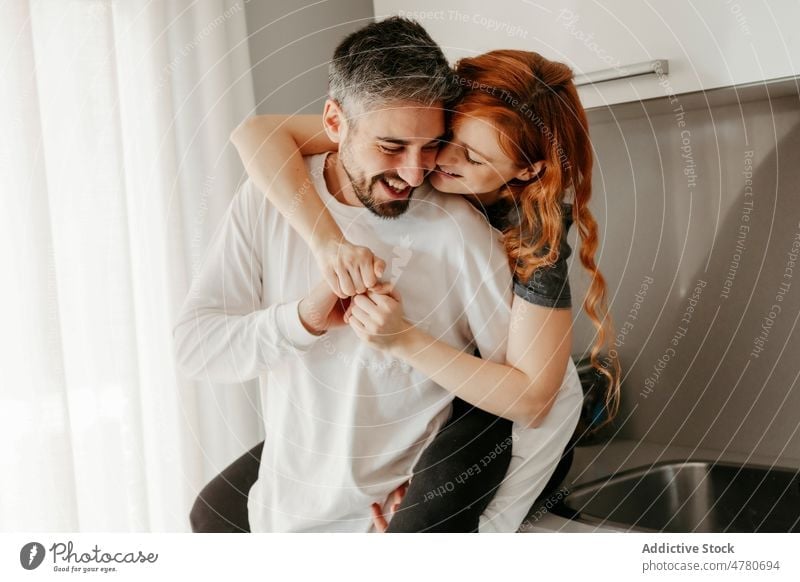 Loving couple hugging in kitchen relationship love bonding cuddle romantic affection piggyback caress embrace fondness redhead together home smile spend time