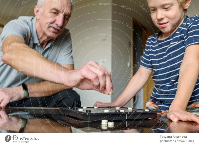 Grandfather with grandson playing checkers grandfather game family board together child senior boy person strategy fun leisure competition indoor man childhood