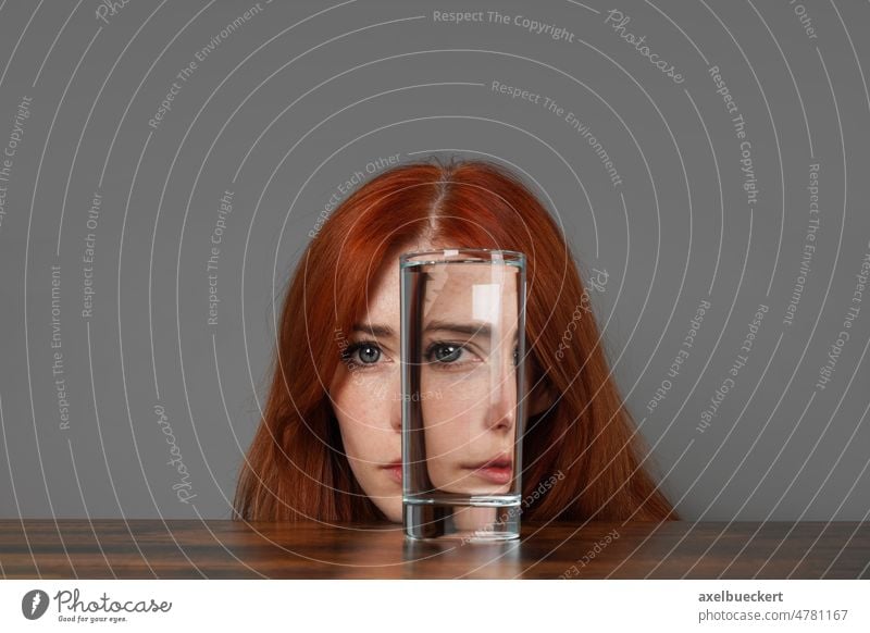 distorted face of woman looking through glass of water introspection duality individuality mood humor surreal identity mid adult refraction creativity illusion