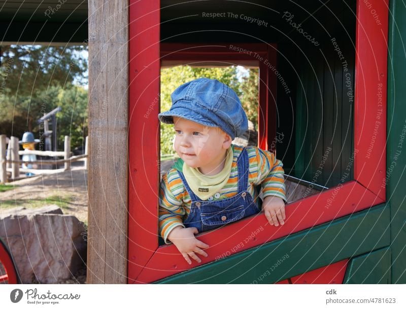 Little boy in the amusement park: traveling in the stagecoach. Human being Child Toddler little boy Denim cap Peaked cap Overalls Striped Blue Green expectant