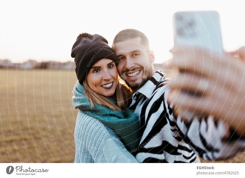 Couple taking a selfie photo with mobile phone in countryside at sunset couple happy together togetherness meadow romance romantic two affection dusk freedom