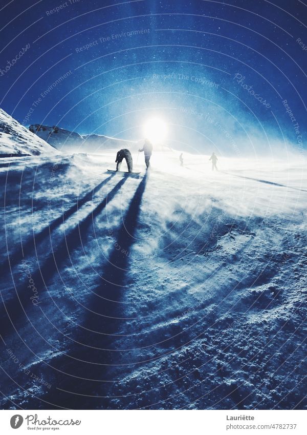 Silhouettes of snowboarders on a ski slope with a snowy sun universe night fantasy planet cosmos outdoor space galaxy blue winter mountain landscape mountains