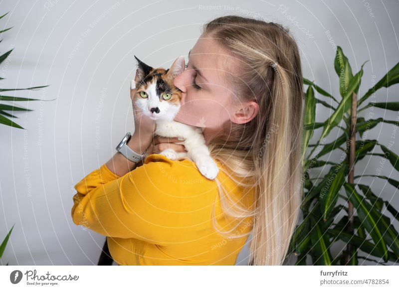 young woman hugging and kissing her cute cat kitty one animal pet owner female person caucasian girl blond hair dress yellow long hair beautiful calico white