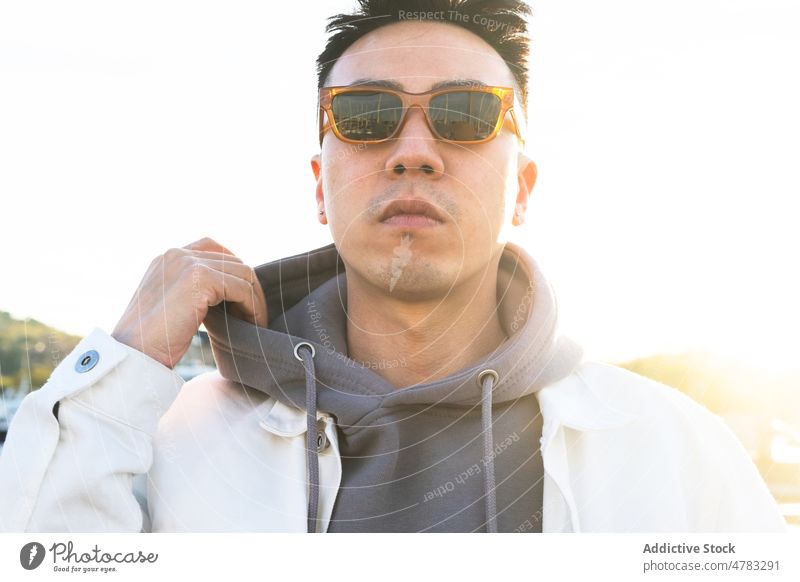Stylish man in sunglasses on street style appearance city trendy fashion confident accessory hoodie male sunlight serious sunshine urban cloudless town summer