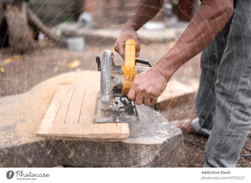 Unrecognizable man cutting wood with grinder woodworker plank board industry countryside instrument production equipment rural occupation environment light tool