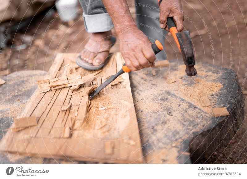 Faceless man carving wood with chisel woodworker carve handwork countryside manufacture handicraft instrument industry production rural occupation light hammer