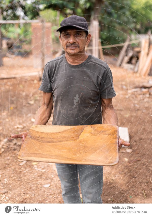 Male master with wooden plate man woodworker tray manufacture handwork countryside handicraft production rural occupation light summer industry job skill