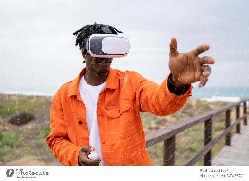Black man exploring virtual reality on seashore vr cyberspace boardwalk futuristic goggles embankment style glasses waterfront immerse african american black
