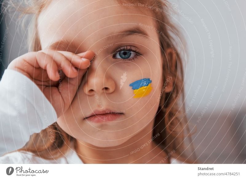Innocent child is crying. Portrait of little girl with Ukrainian flag make up on the face ukraine portrait expression innocent kid standing posing message