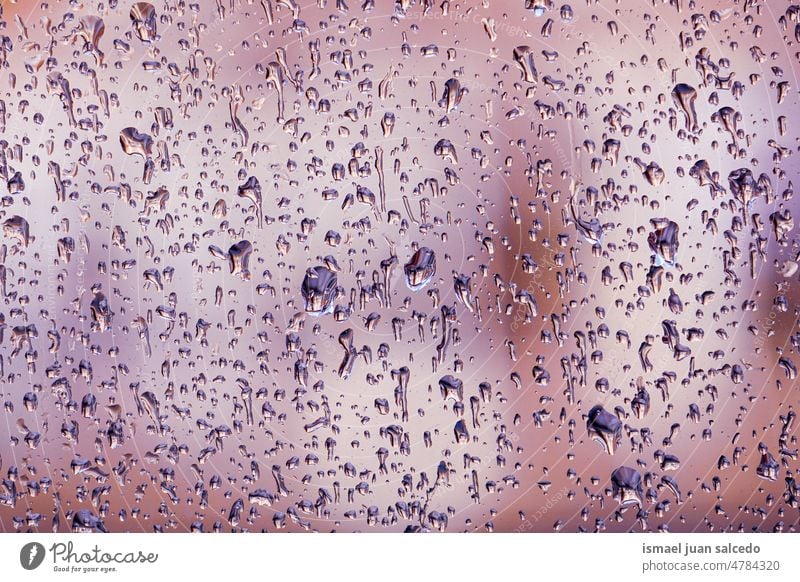 raindrops on thye window in rainy days water wet glass gray grey blue transparent surface closeup abstract background textured bright splash droplet