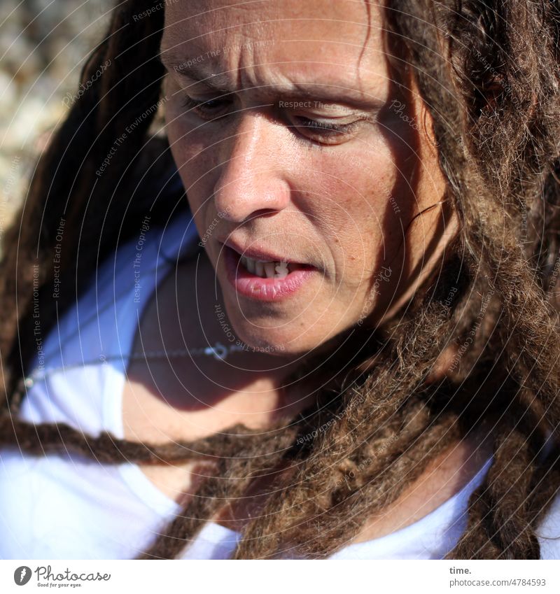 Woman, concentrated portrait Curl rastas T-shirt Necklace ersnt sunny Penumbra Furrowed brow observantly employed focused
