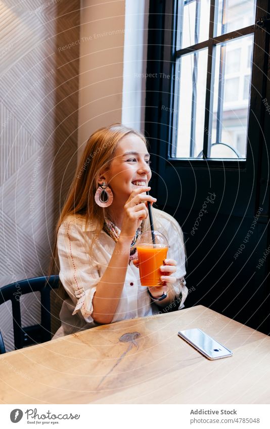 Happy young woman drinking juice in cafe enjoy cup fruit happy joyful blonde vegetarian vegan female fresh diet detox vitamin meal food natural orange