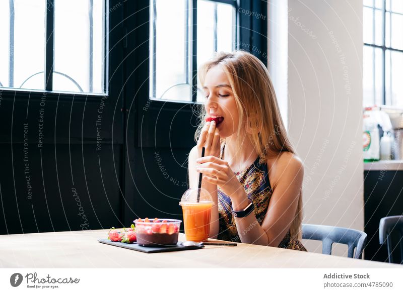 Young woman eating strawberry dessert in cafe women breakfast healthy smoothie bowl juice enjoy fruit orange young modern happy female food fresh diet detox