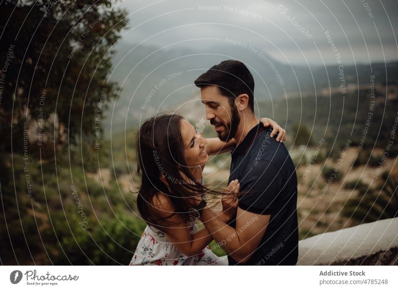 Loving couple embracing while standing against rural valley embrace love happy smile hugging countryside summer green foggy hill casual young adult nature