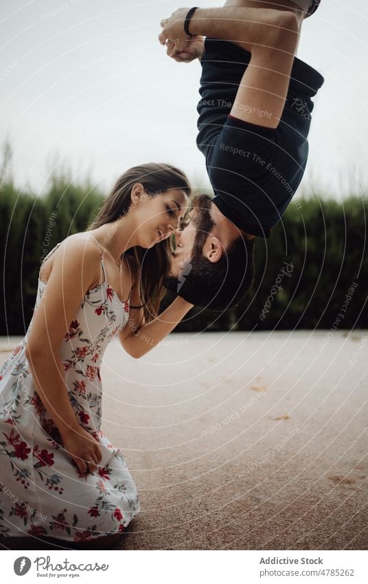 Tender couple kissing upside down on rural street tender casual creative hanging countryside valentine bonding balance summer love strong contrast young adult