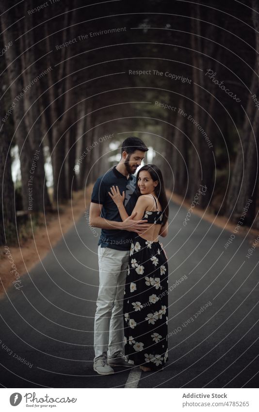 Loving couple embracing on pathway in misty forest alley loving mysterious romantic solitude casual hug road tree asphalt tranquil young adult love travel