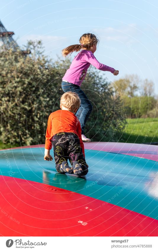 2 children jumping on a bouncy cushion in the park Bouncy cushion Hop Jump Romp Movement Girl Boy (child) Playing Joy Child Exterior shot Infancy