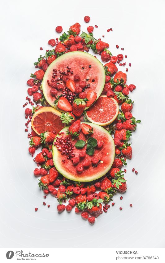 Heap of various red summer fruits: watermelon, grapefruit, raspberries, strawberries and pomegranate seeds on white background. heap healthy sweet fruit salad