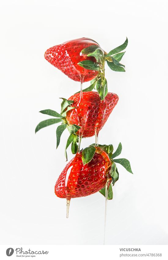 Honey dripping from flying red strawberries at white background honey delicious healthy sweet food levitating air liquid fruit front view berry concept fresh