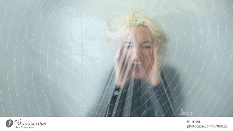 panorama banner of blurred portrait of a young blonde woman behind transparent plastic foil as a symbol of fear, panic, worry and despair wide copy space