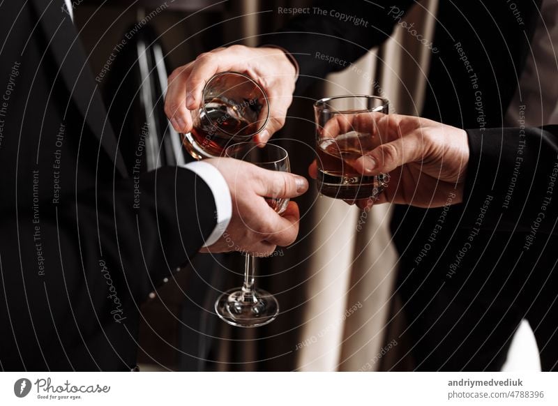 Business meeting. Men hold glasses of whiskey. Men's Party. Hand with a drink of alcohol man toasting hands young party holding happy gold fun people friends