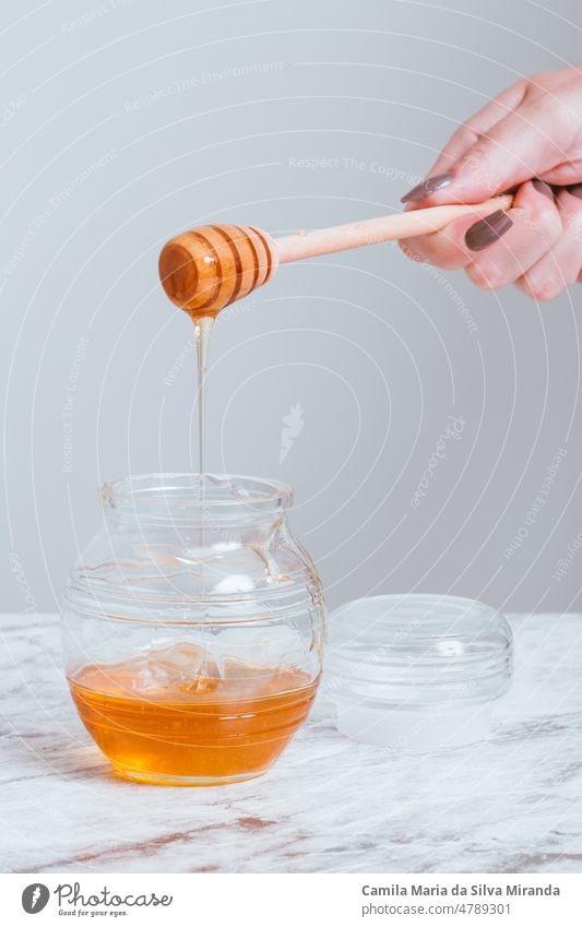 Delicate female hand with honey pot. background bee closeup delicious eating food fresh health healthy holding ingredient natural nature organic spoon sweet