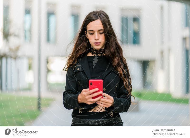 Young woman in black using her phone outside young black color clothes red city front view building person outdoor female street urban lifestyle mobile