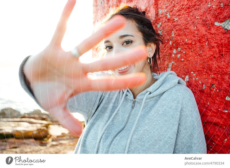 Young woman saluting to camera portrait while traveling summer sunny day holiday and vacation concept. Light beam and motion concept. Happy and vibrant life portrait. Traveling alone woman concept.